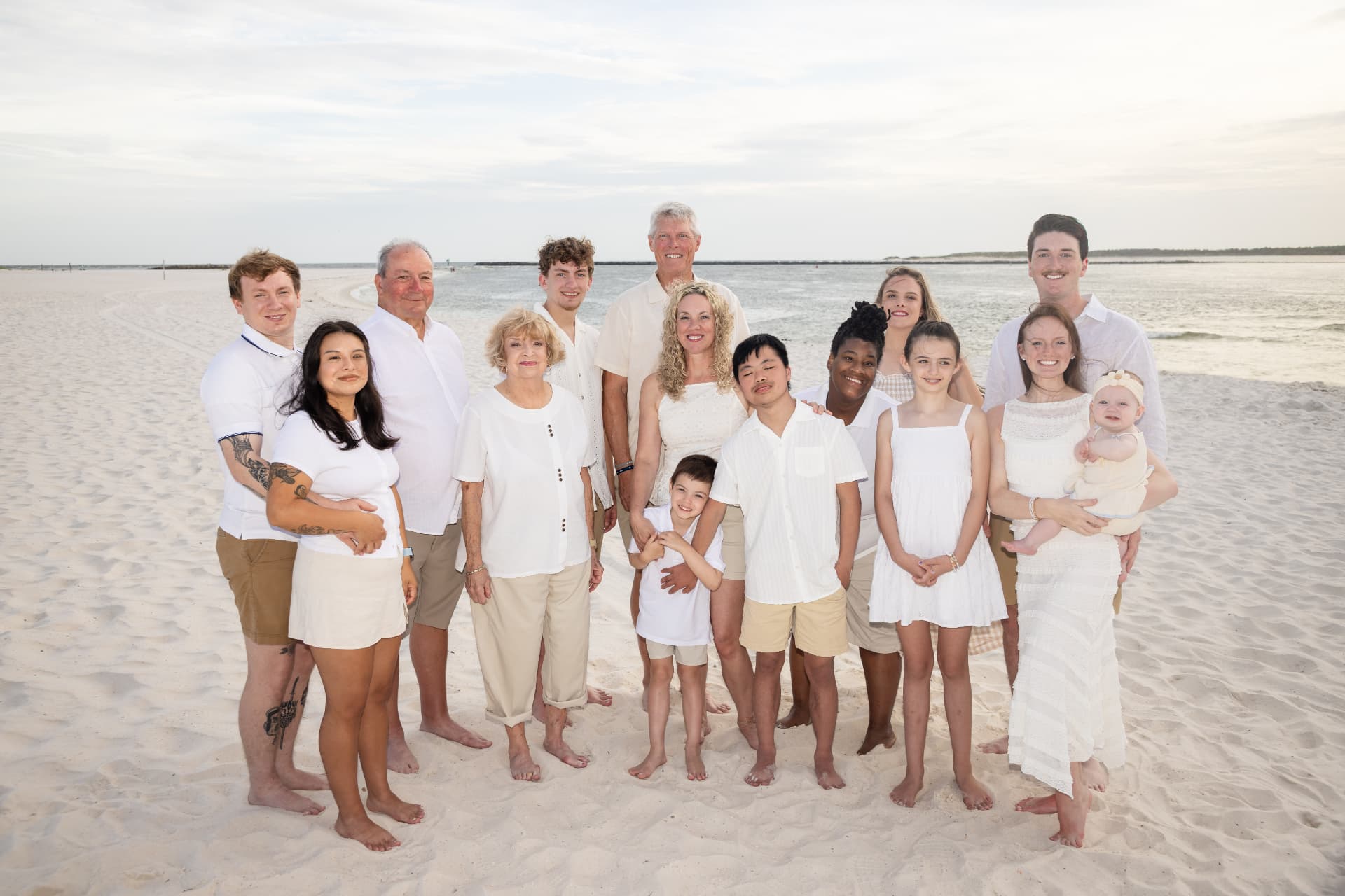 Large family portrait on the beach at sunset in white and cream tones