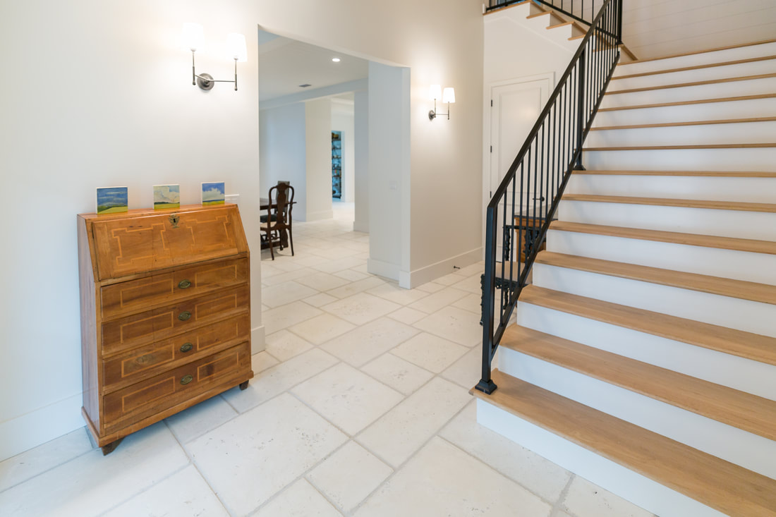 Bright interior foyer with wooden staircase and antique desk