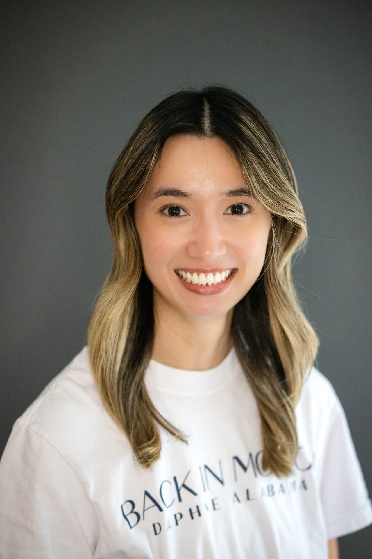Professional headshot of a woman with warm smile against a gray backdrop